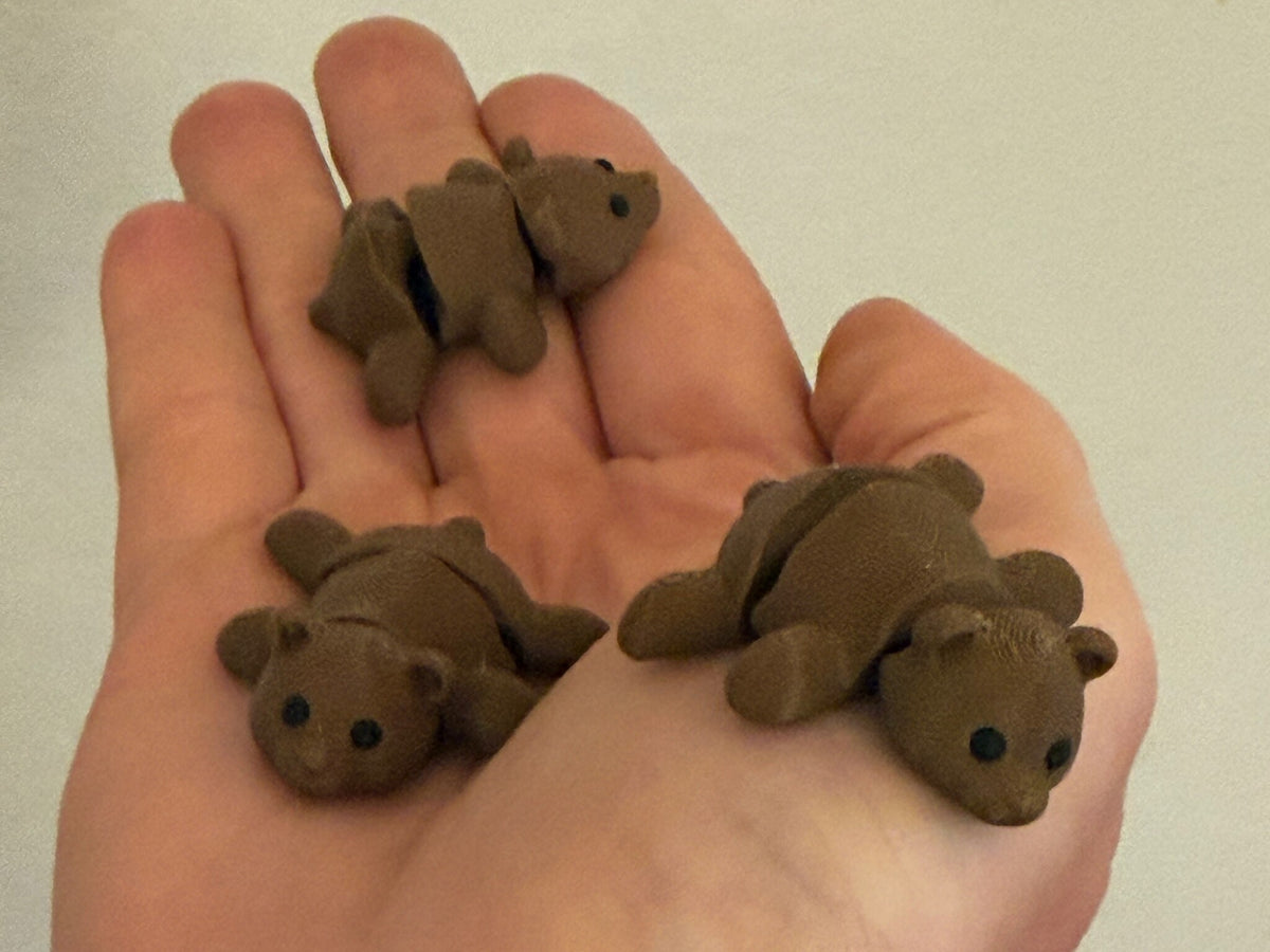 Three Mini Flexi Bears held in an open hand to show their small size
