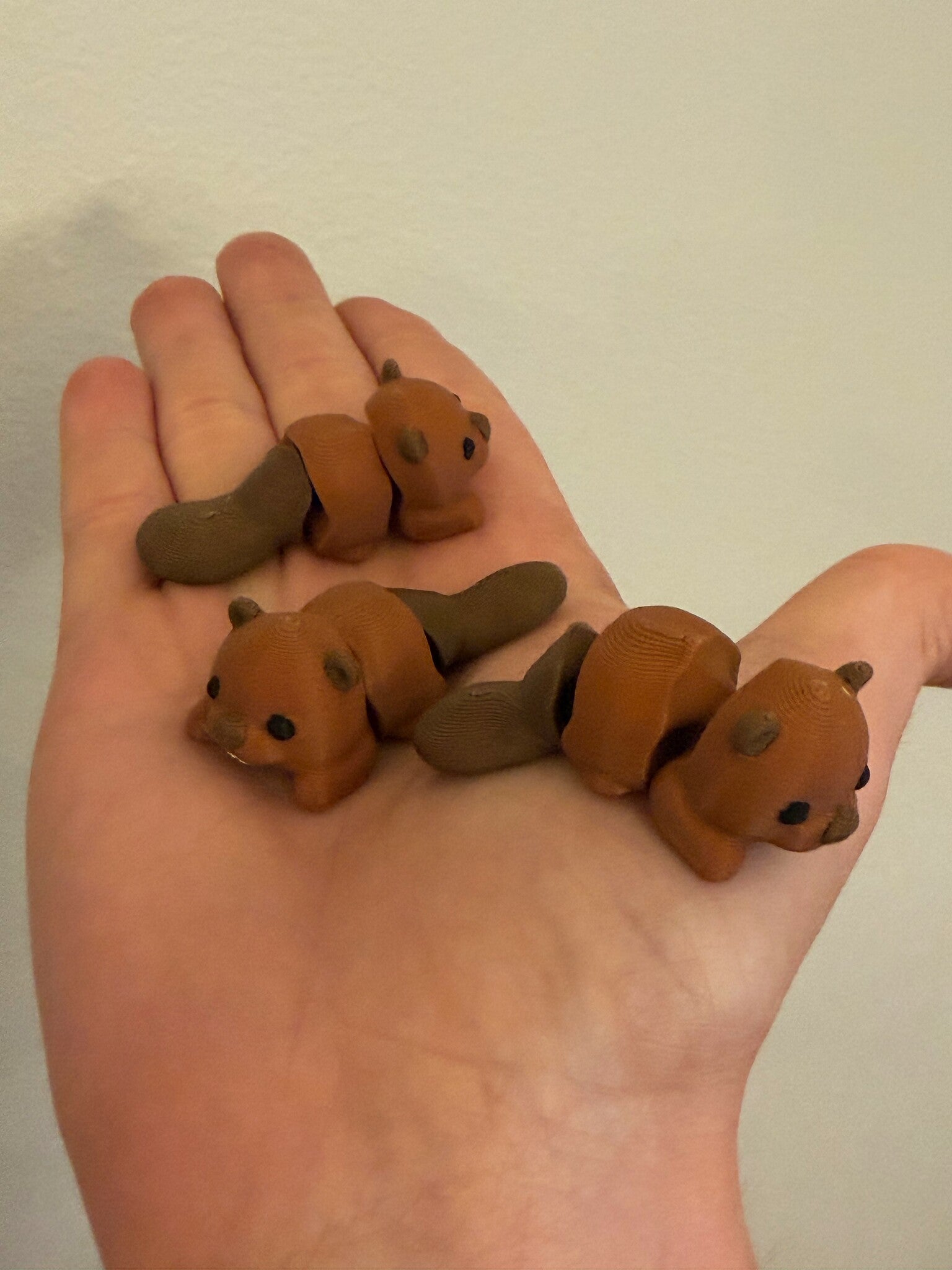 Three Mini Flexi Beavers held in an open hand to show their small size