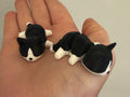Two black and white tuxedo 3D printed Mini Flexi Cats resting in an open palm