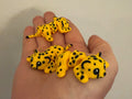 Three yellow spotted 3D printed Mini Flexi Cheetahs resting in an open hand