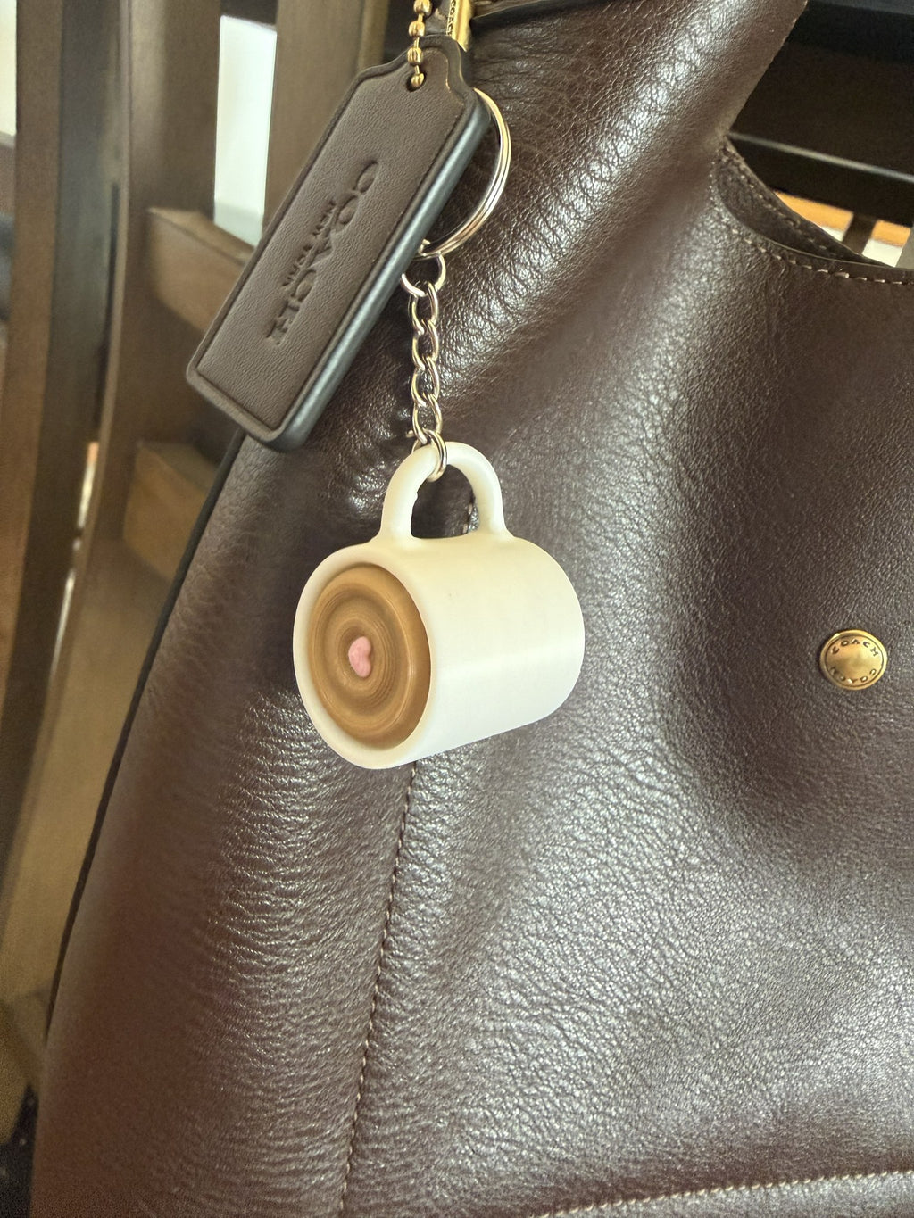 Coffee Cup Clicker Keychain clipped to the strap of a brown leather handbag