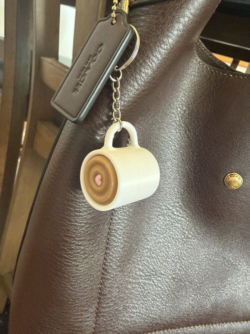 Coffee Cup Clicker Keychain clipped to the strap of a brown leather handbag