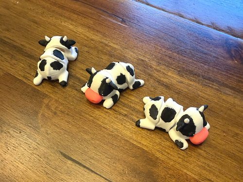 Three flexi Holstein cows on a table shown from multiple angles