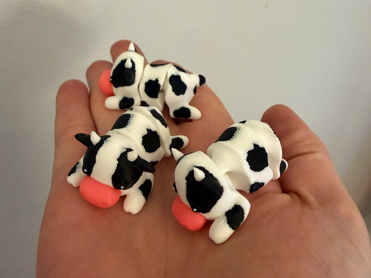 Four Mini Flexi Cows held in an open hand to show their small size