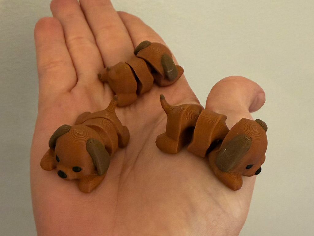 Three Mini Flexi Dogs held in an open hand to show their small size