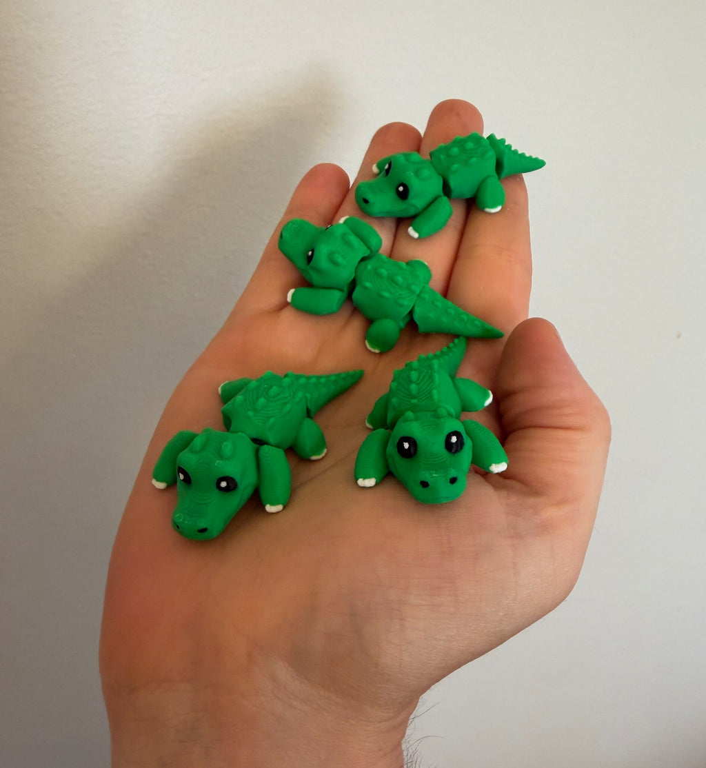 Five mini flexi alligators resting in an open hand to show their pocket size