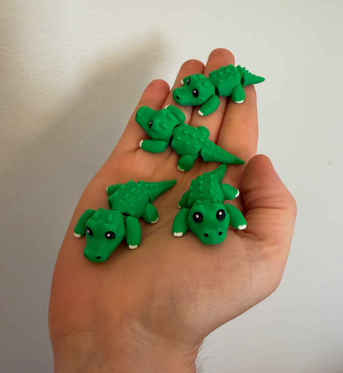 Five mini flexi alligators resting in an open hand to show their pocket size