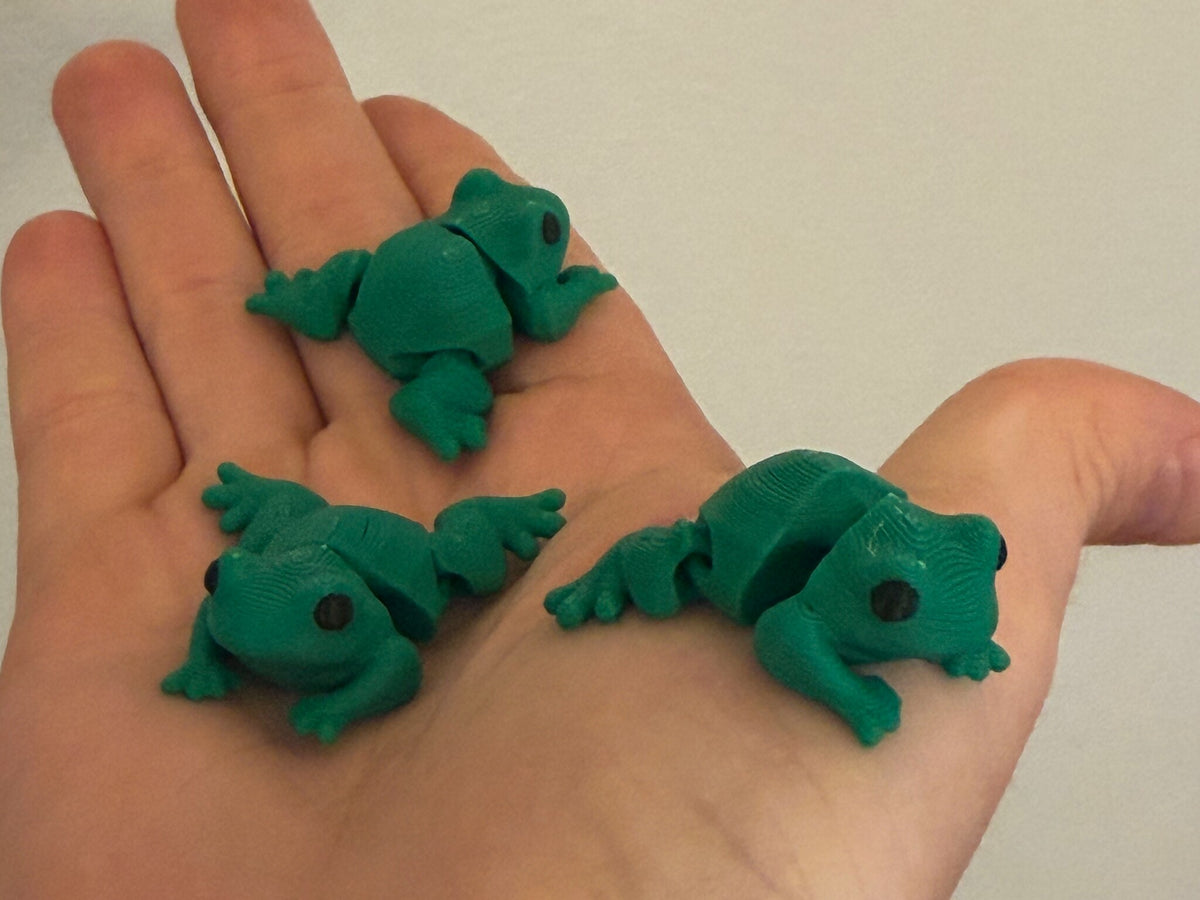 Three Mini Flexi Frogs held in an open hand to show their small size