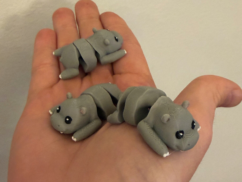 Three Mini Flexi Hippos held in an open hand to show their small size