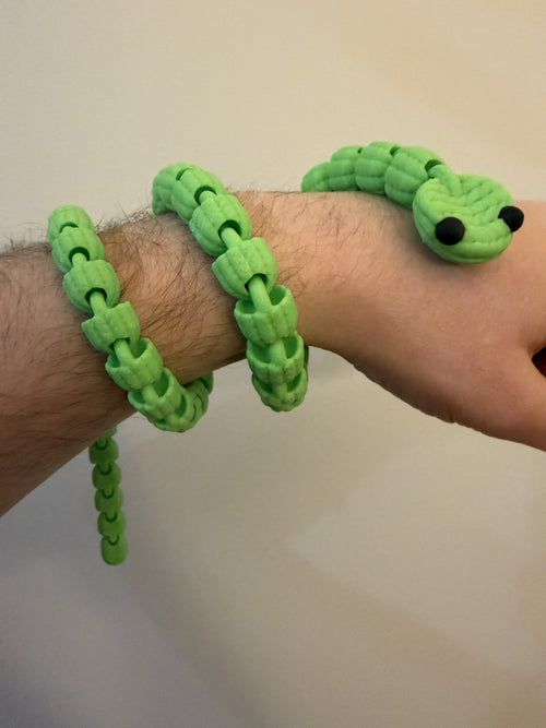 Green 3D printed Knit Articulated Snake coiled around a wrist, showing its flexible knit-textured segments