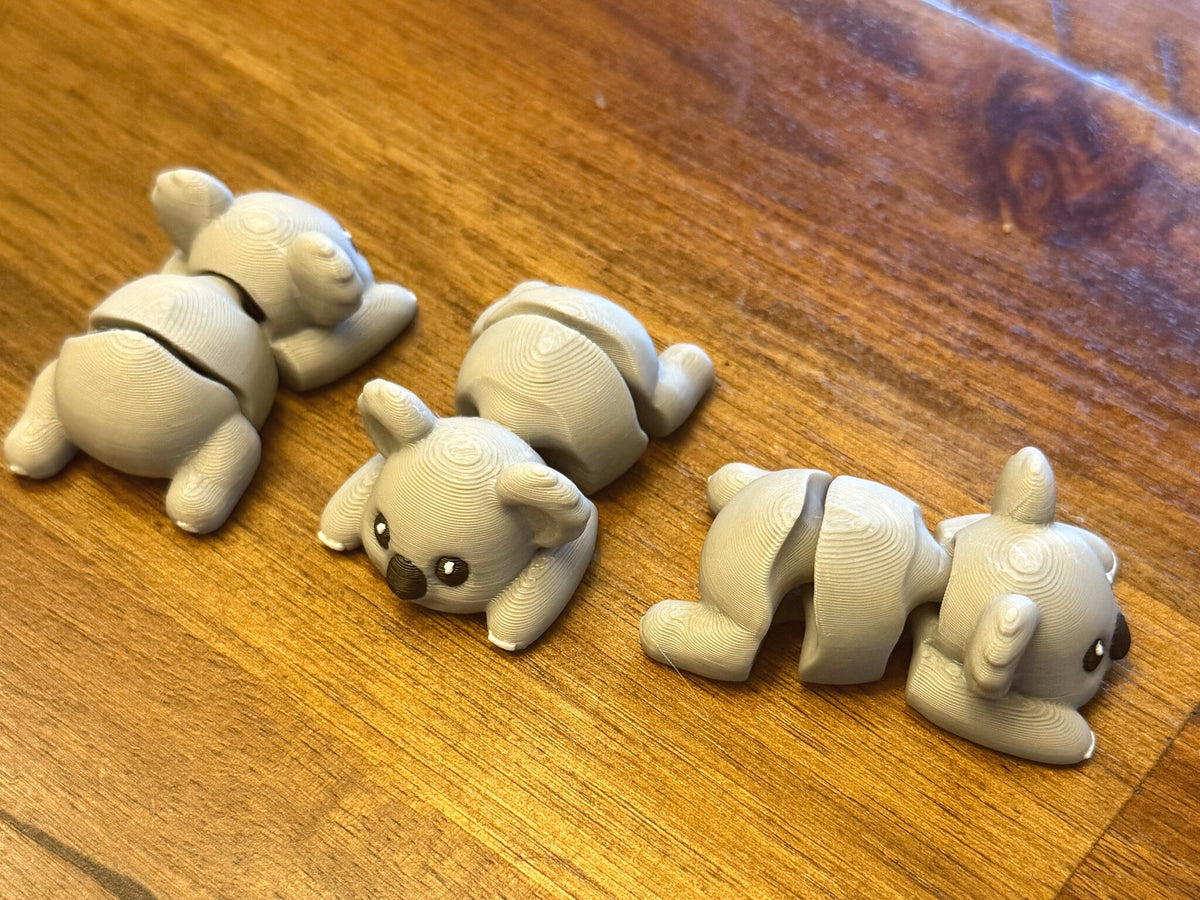 Four grey flexi koalas posed together on a table
