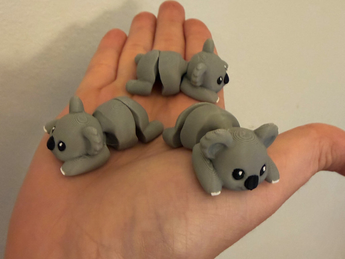 Three Mini Flexi Koalas held in an open hand to show their small size