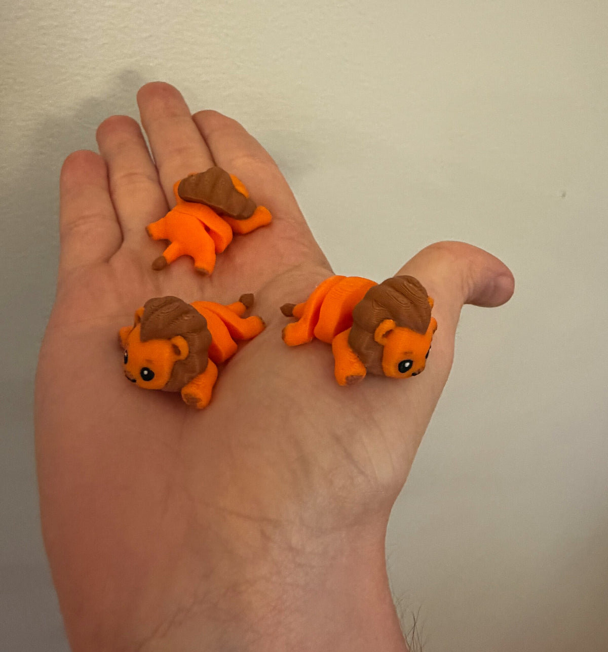 Three Mini Flexi Lions held in an open hand to show their small size