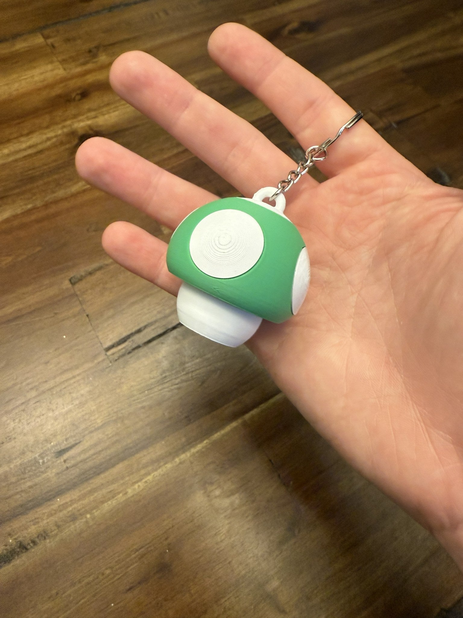 Green Mushroom Clicker Keychain resting in an open hand to show its size