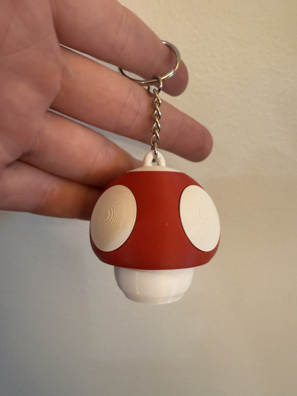 Red Mushroom Clicker Keychain with cream spots hanging from a keyring