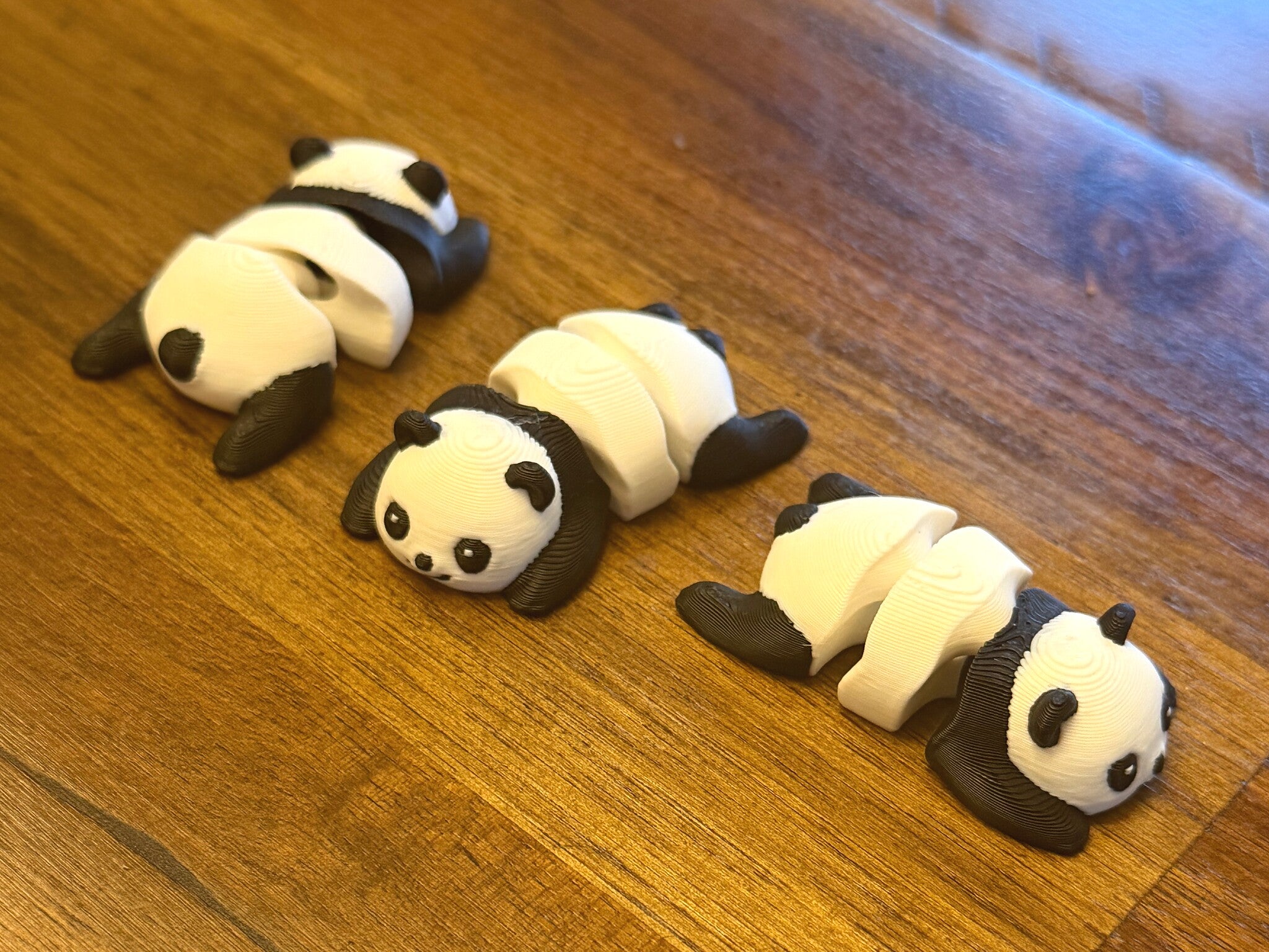 Three flexi pandas lined up on a wood table