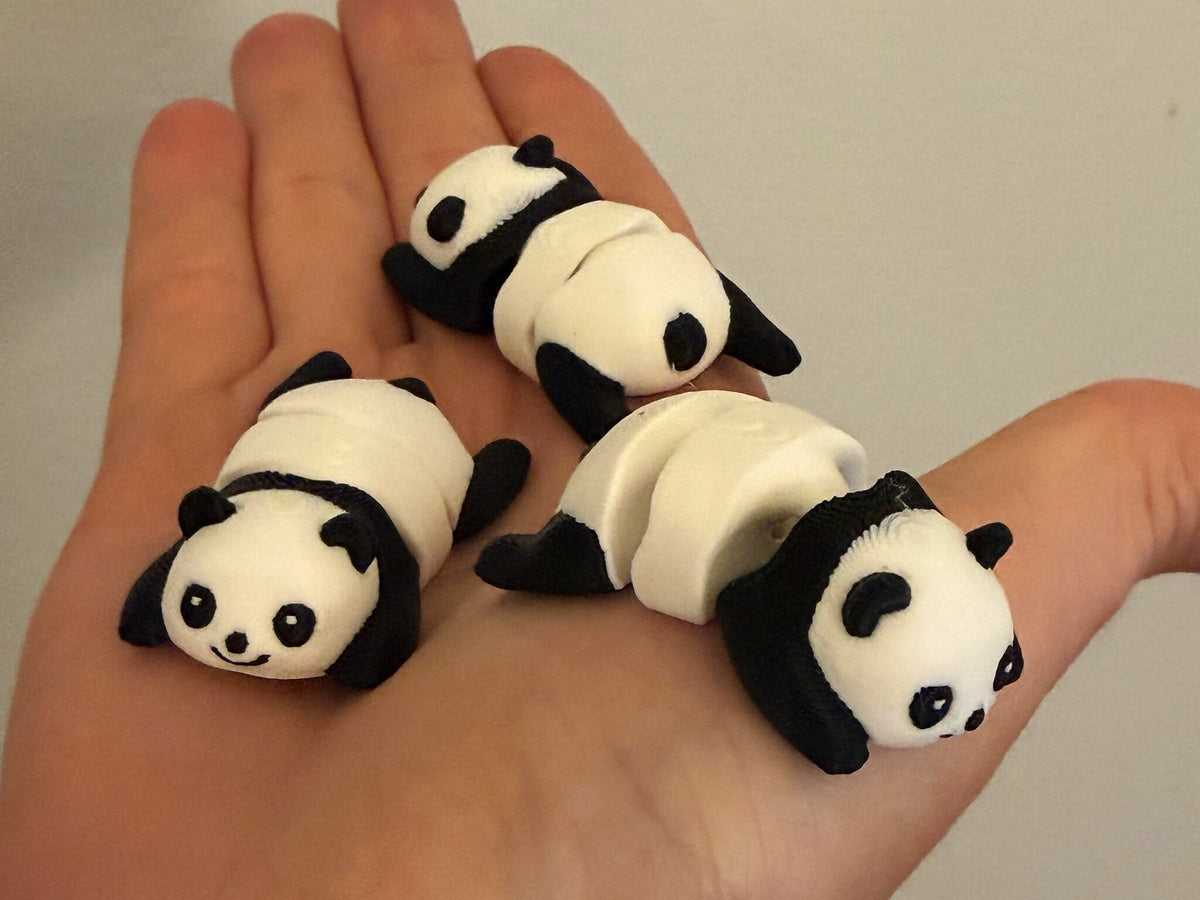 Three Mini Flexi Pandas held in an open hand to show their small size