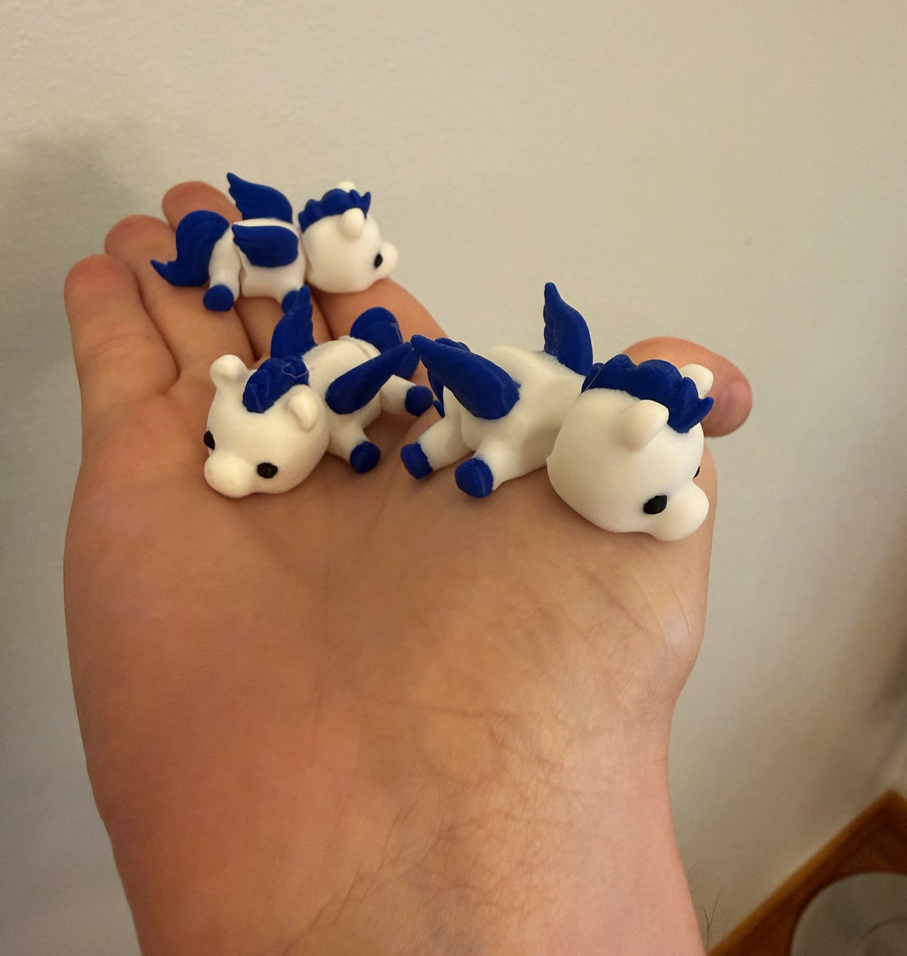 Three Mini Pegasus figurines held in an open hand to show their small size