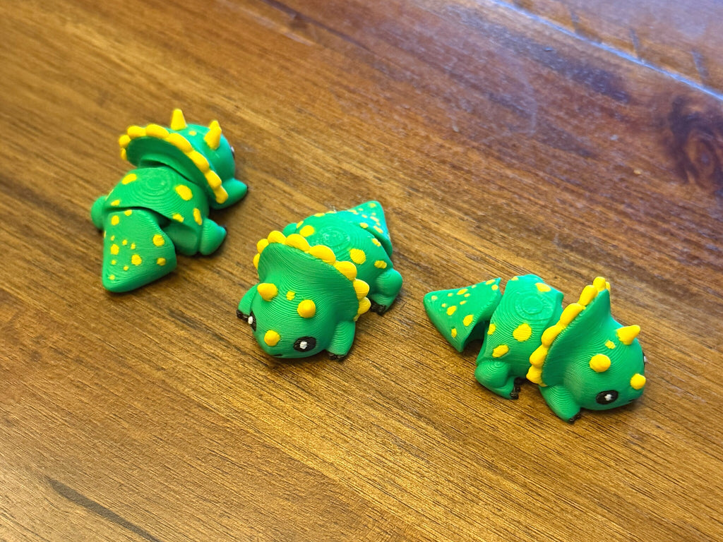 Three flexi triceratops on a table shown from multiple angles