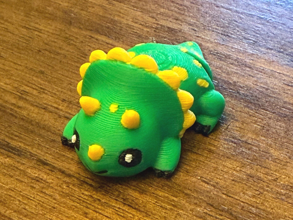 Close-up of a single green flexi triceratops with yellow frill spikes and spots, three-quarter view
